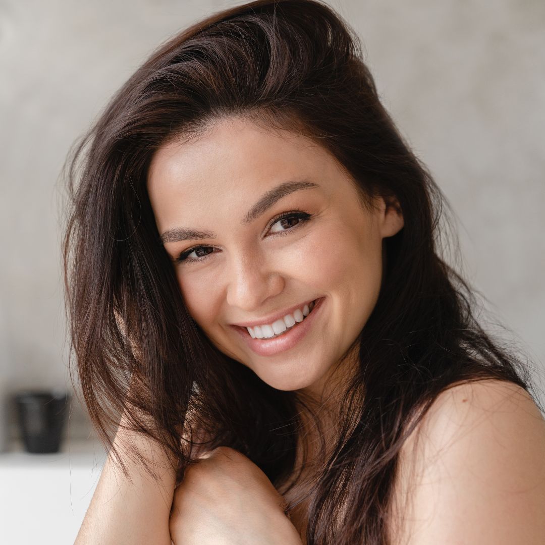 Brunette woman with her hair parted to the side and smiling.